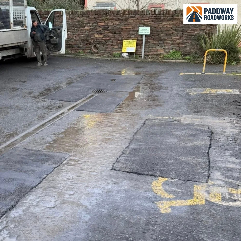 Broken and cracked tarmac in a parking bay marked up before a pothole repair
